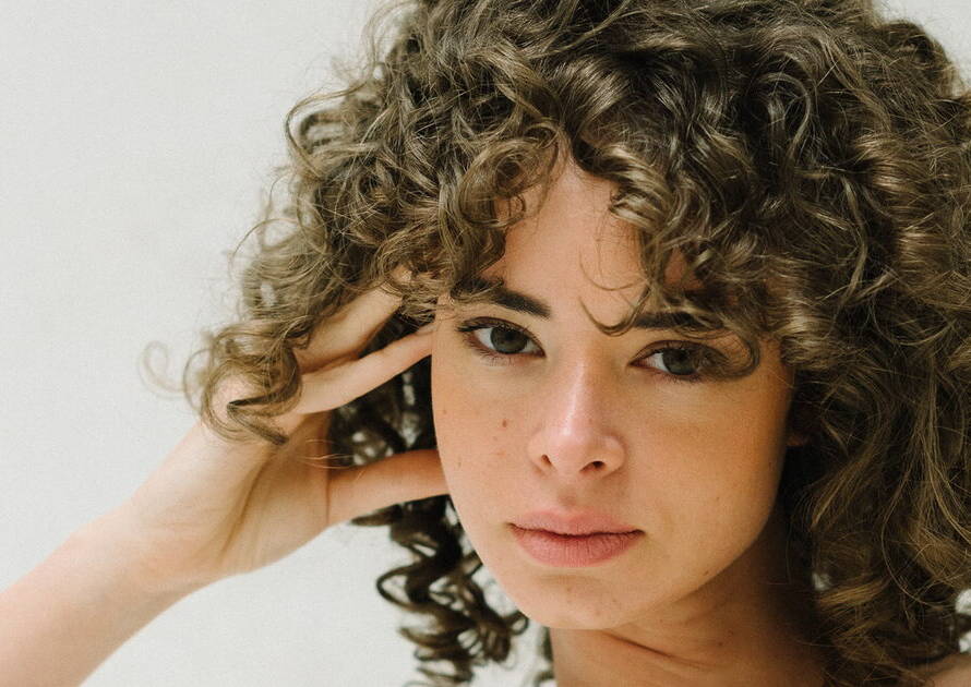 Mujer con cabello rizado y encrespado tratado con productos naturales en peluquería orgánica de Cuenca